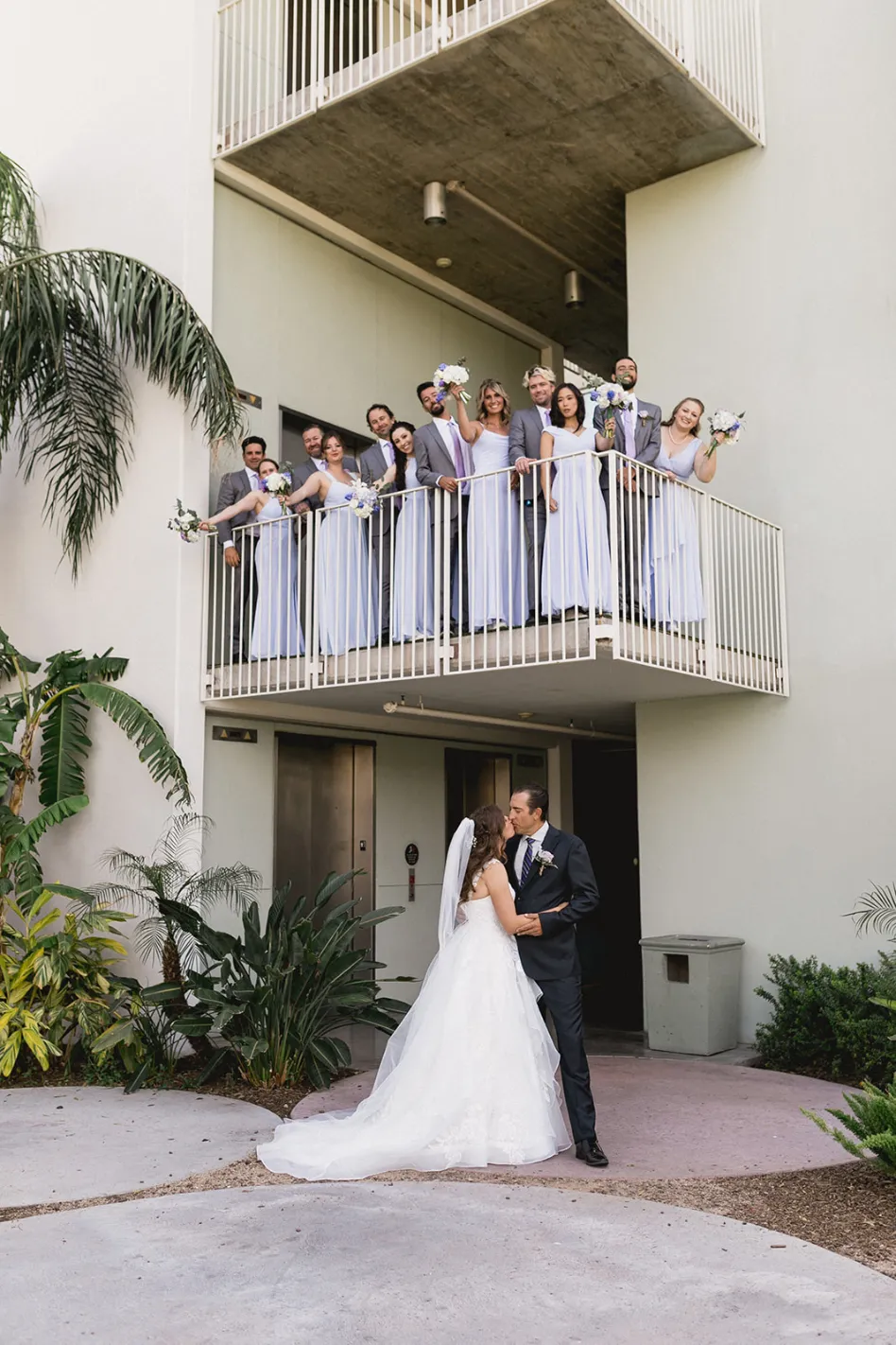 jacqueline and joel kissing with bride tribe on balcony